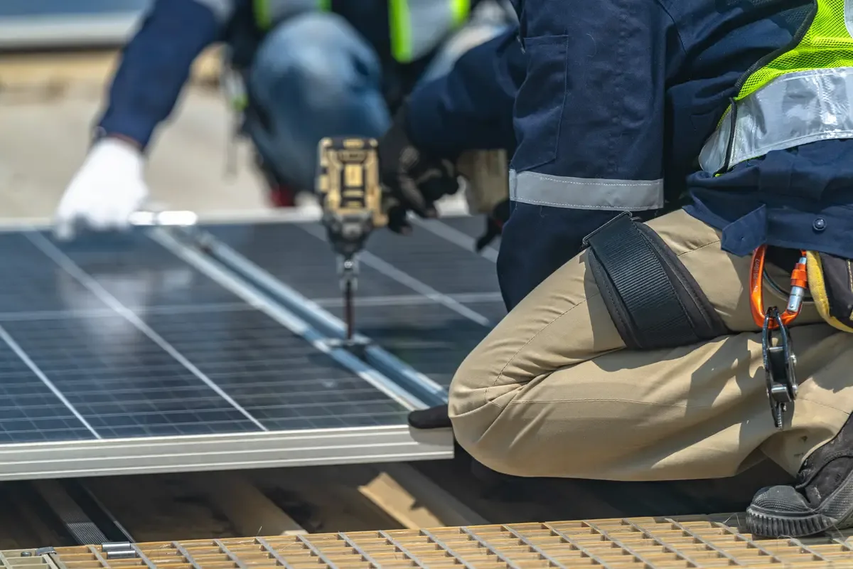 Técnico atornillando un panel solar a su estructura de montaje en una cubierta de Sabadell